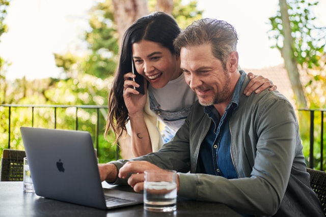 Couple Using Laptop with Woman Calling Brokerage